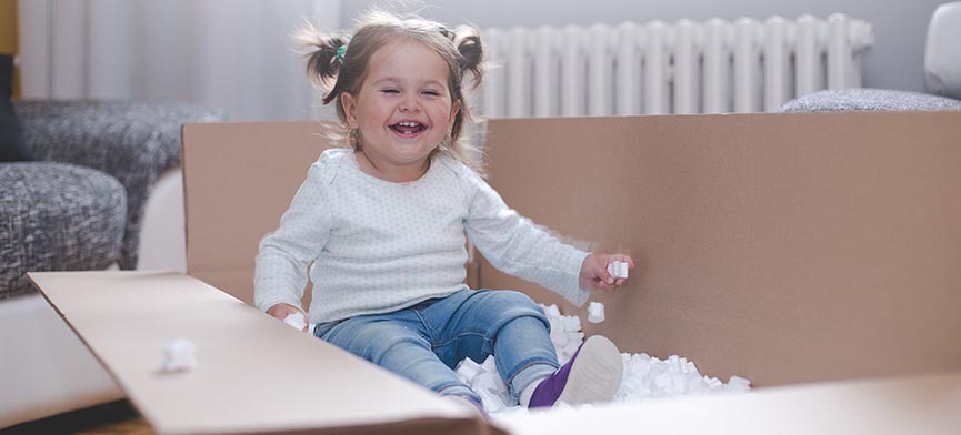 female toddler playing in moving box with packing peanuts